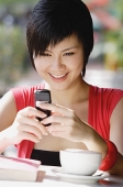 Woman at cafe using mobile phone, text messaging - Asia Images Group
