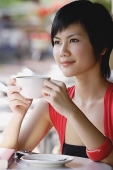 Woman having cup of coffee, looking away - Asia Images Group