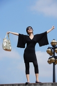 Woman dressed in black, arms outstretched - Asia Images Group