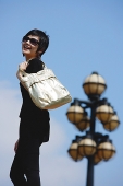 Woman dressed in black, carrying bag over shoulder - Asia Images Group