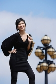 Woman dressed in black, carrying bag over shoulder, smiling at camera - Asia Images Group