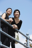 Women leaning on railing, smiling, looking away - Asia Images Group