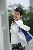 Mature woman carrying shopping bags, looking over shoulder - Asia Images Group