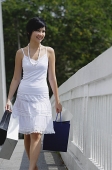 Woman dressed in white carrying shopping bags - Asia Images Group