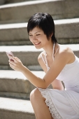 Woman sitting on steps, using mobile phone - Asia Images Group