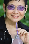 Woman with bottled drink and straw, smiling - Asia Images Group