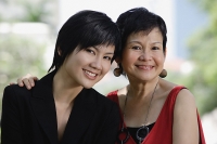 Mother and adult daughter looking at camera, head shot - Asia Images Group