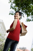 Mature woman with shopping bags, turning to look over shoulder - Asia Images Group