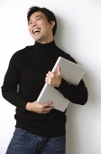 Man hugging laptop, laughing - Asia Images Group