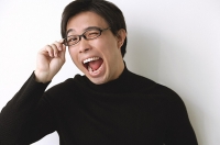 Man in black turtleneck, adjusting glasses, mouth open - Asia Images Group