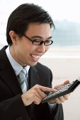 Businessman using calculator, smiling - Asia Images Group
