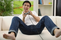Man playing with video game at home - Asia Images Group
