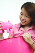Woman holding pink piggy bank - Asia Images Group