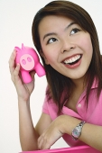 Woman holding pink piggy bank to ear - Asia Images Group