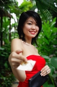 Woman in red tube top, holding credit card towards camera - Asia Images Group