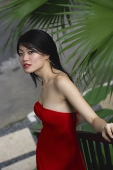Woman in red dress, leaning on railing, looking at camera - Asia Images Group