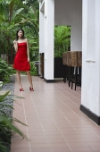 Woman in red dress, standing outside building - Asia Images Group
