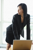 Businesswoman with laptop, standing, looking away - Asia Images Group