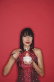 Woman dressed in red, holding bowl of rice - Asia Images Group