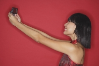 Woman using mobile phone to take a picture of herself - Asia Images Group