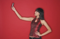 Woman using mobile phone to take a picture of herself, hand on hip - Asia Images Group