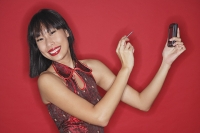 Woman against red background, holding PDA, smiling at camera - Asia Images Group