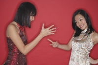 Two women in cheongsams, playing hand game - Asia Images Group