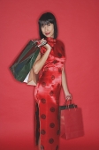 Woman in red cheongsam, carrying shopping bags - Asia Images Group
