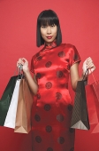One woman in red Chinese dress, carrying shopping bags - Asia Images Group