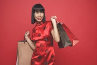Woman in red cheongsam with shopping bags - Asia Images Group