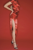 Woman wearing cheongsam and high heels, hands on hips - Asia Images Group