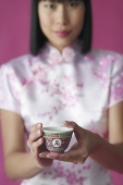 Woman holding Chinese tea cup towards camera - Asia Images Group