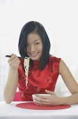 Woman holding chopsticks with noodles on it - Asia Images Group