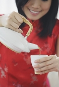 Woman pouring tea from teapot - Asia Images Group