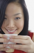 Woman holding teacup, smiling at camera - Asia Images Group