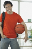 Man in red T shirt and jeans, holding basketball - Asia Images Group