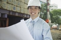 Businessman with blueprints, smiling at camera - Asia Images Group