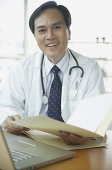 Doctor smiling at camera, holding folder - Asia Images Group
