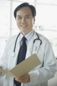 Doctor smiling at camera, holding folder - Asia Images Group