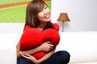 Young woman embracing pillow, smiling at camera - Asia Images Group