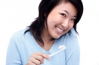 Young woman with toothbrush, smiling at camera - Asia Images Group