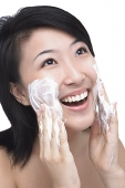Young woman putting facial cleanser on her face - Asia Images Group