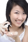 Young woman putting moisturizer on hand - Asia Images Group