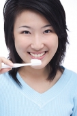 Young woman brushing teeth, smiling at camera - Asia Images Group