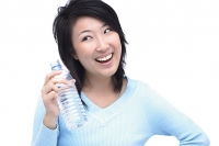 Young woman holding bottle of water, looking away - Asia Images Group