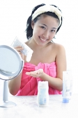 Young woman sitting at dressing table, smiling at camera - Asia Images Group