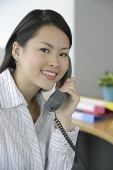 Young woman in office using telephone, portrait - Asia Images Group