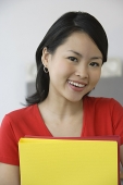 Young woman with folders, smiling at camera - Asia Images Group