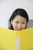 Young woman holding folder, smiling at camera - Asia Images Group
