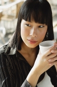 Businesswoman holding cup, looking away - Asia Images Group